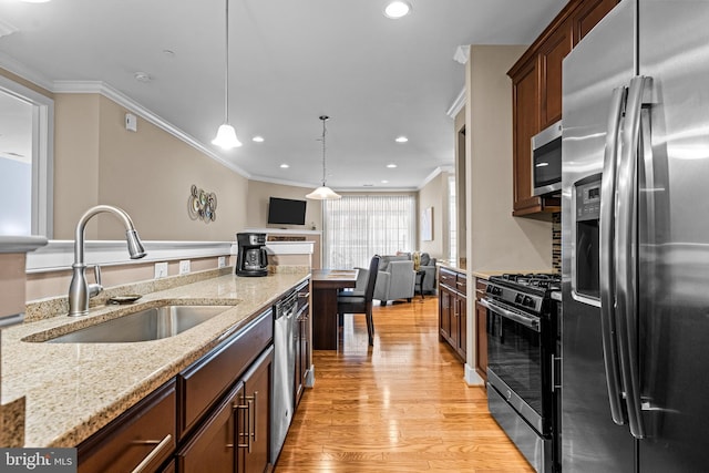 kitchen with light wood-type flooring, ornamental molding, stainless steel appliances, and a sink