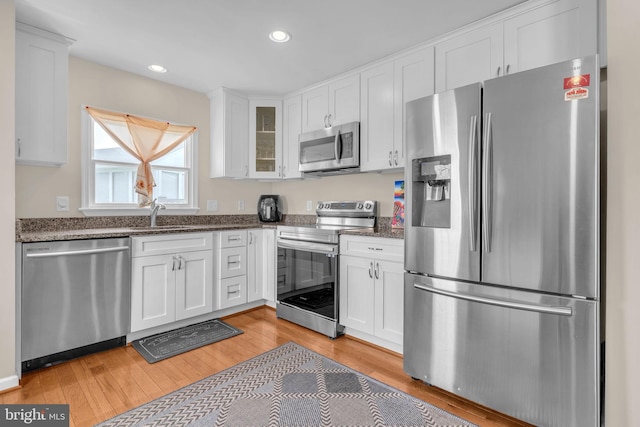 603 N York Rd, Sterling, VA 20164 - kitchen with stainless steel appliances, a sink, white cabinetry, light wood-type flooring, and glass insert cabinets