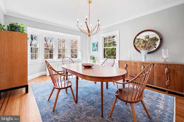 dining area with light wood-style flooring, ornamental molding, and a notable chandelier