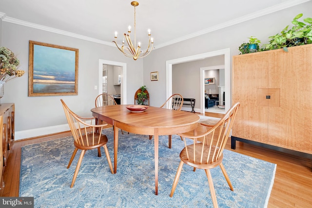 dining space featuring a chandelier, ornamental molding, wood finished floors, and baseboards