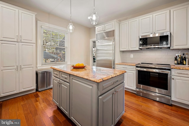 kitchen with white cabinets, hardwood / wood-style flooring, a center island, gray cabinets, and stainless steel appliances