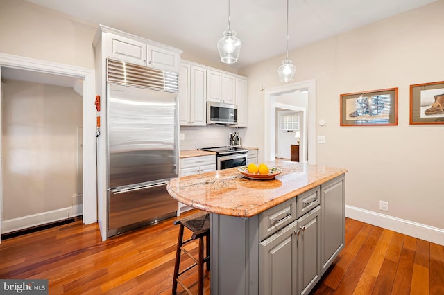 kitchen featuring stainless steel appliances, white cabinetry, backsplash, gray cabinets, and wood-type flooring