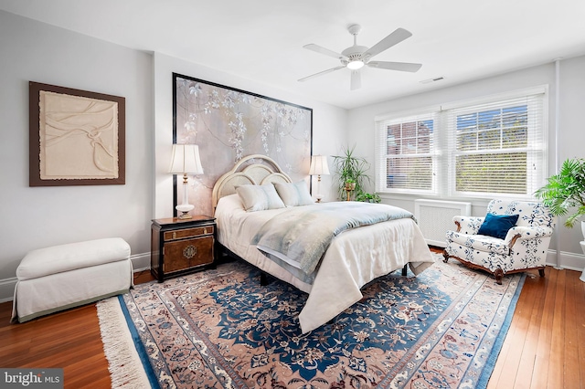 bedroom featuring hardwood / wood-style flooring, visible vents, baseboards, and ceiling fan