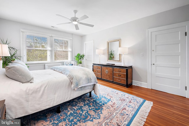 bedroom featuring a ceiling fan, baseboards, and wood finished floors