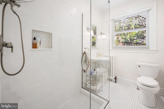 bathroom featuring tile patterned flooring, baseboards, tiled shower, and toilet