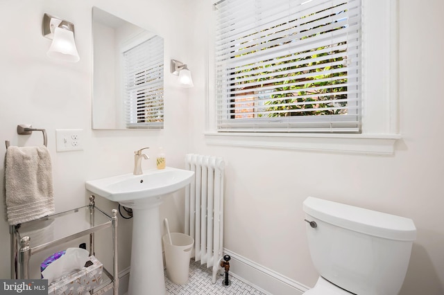 half bath featuring toilet, radiator heating unit, and baseboards