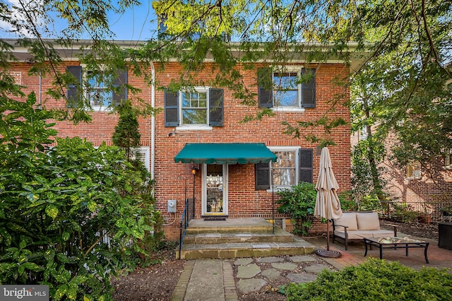 view of front of property with an outdoor hangout area, a patio, and brick siding