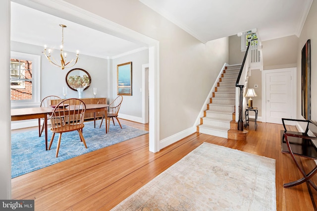 dining space with crown molding, stairway, hardwood / wood-style floors, an inviting chandelier, and baseboards