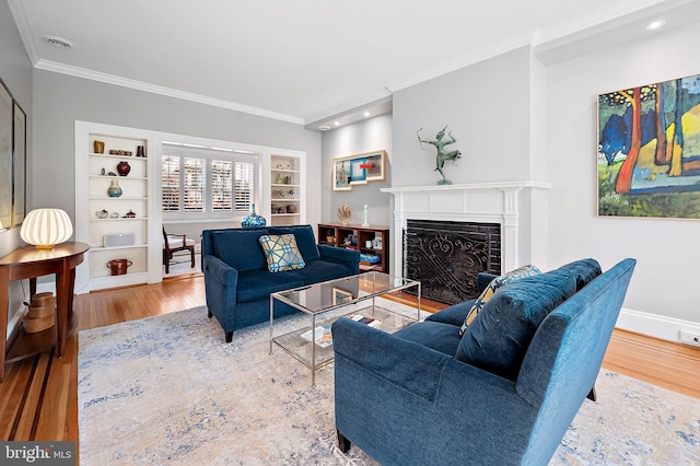 living area with a fireplace, wood finished floors, visible vents, baseboards, and crown molding