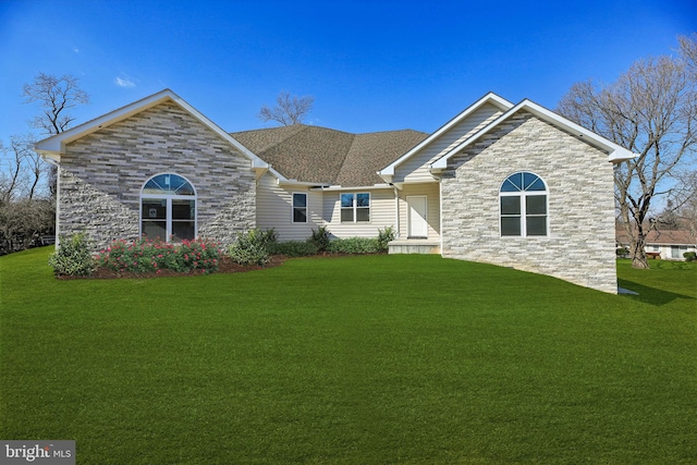 view of front of house with stone siding, a front lawn, and roof with shingles