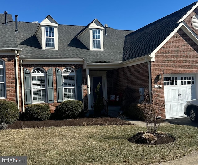 view of front facade featuring a front yard, brick siding, an attached garage, and roof with shingles