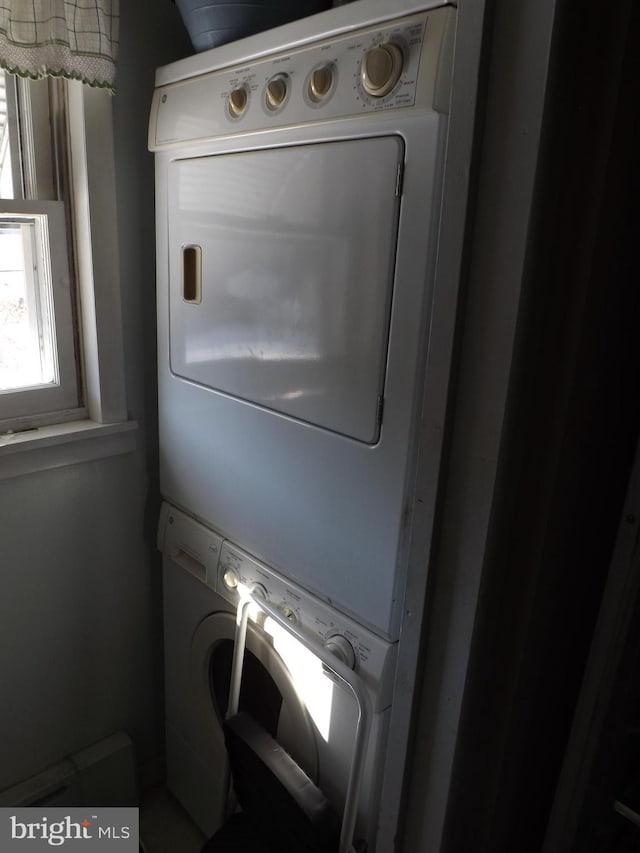 clothes washing area featuring stacked washer and dryer and laundry area