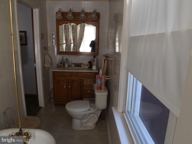 bathroom featuring tile patterned flooring, toilet, vanity, and tile walls