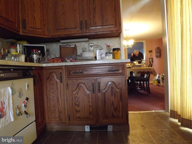 kitchen featuring a notable chandelier, dark tile patterned flooring, visible vents, light countertops, and brown cabinetry