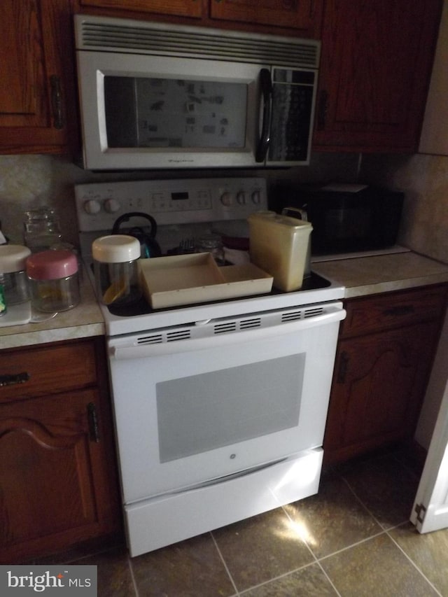 kitchen with electric stove, light countertops, stainless steel microwave, decorative backsplash, and tile patterned flooring