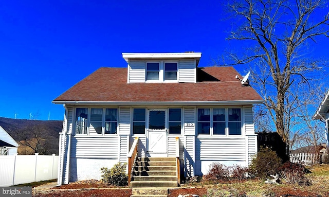 bungalow-style house featuring a shingled roof and fence