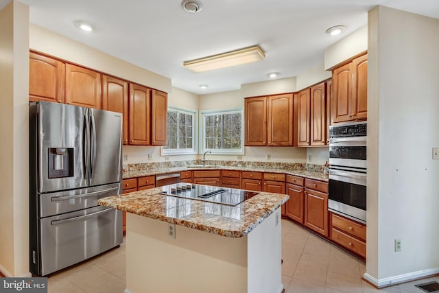 kitchen with visible vents, a kitchen island, light stone countertops, stainless steel appliances, and a sink