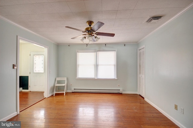 spare room with baseboards, visible vents, ornamental molding, hardwood / wood-style floors, and baseboard heating