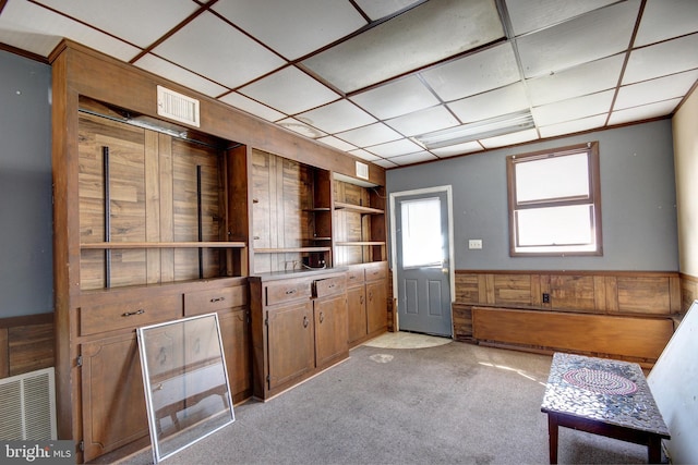 interior space with a wainscoted wall, wooden walls, visible vents, and light colored carpet