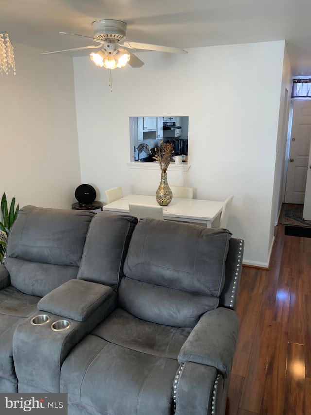 living area featuring baseboards, dark wood-type flooring, and a ceiling fan