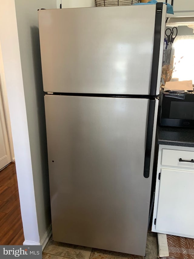 interior details with dark countertops, white cabinetry, and freestanding refrigerator