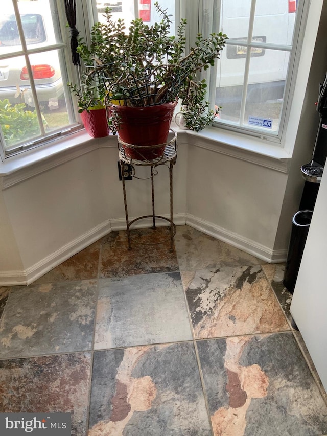 unfurnished dining area with stone finish flooring and baseboards