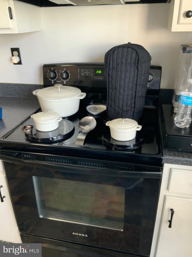 interior details featuring dark countertops, white cabinets, and black electric range oven