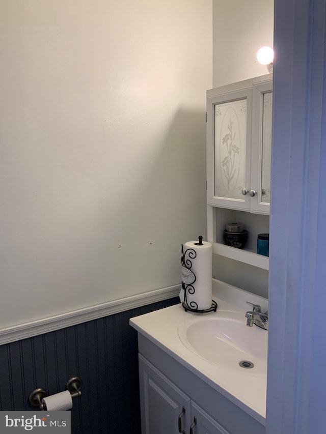 bathroom with vanity and a wainscoted wall