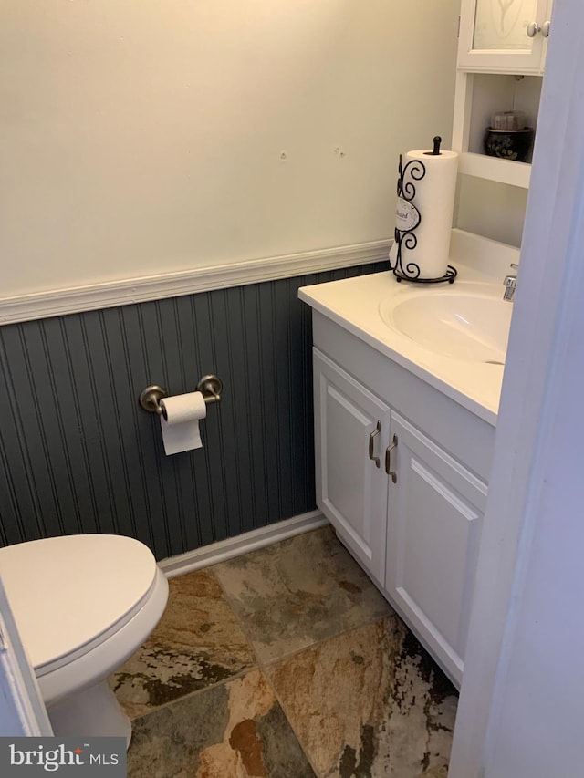 bathroom with vanity, toilet, and wainscoting