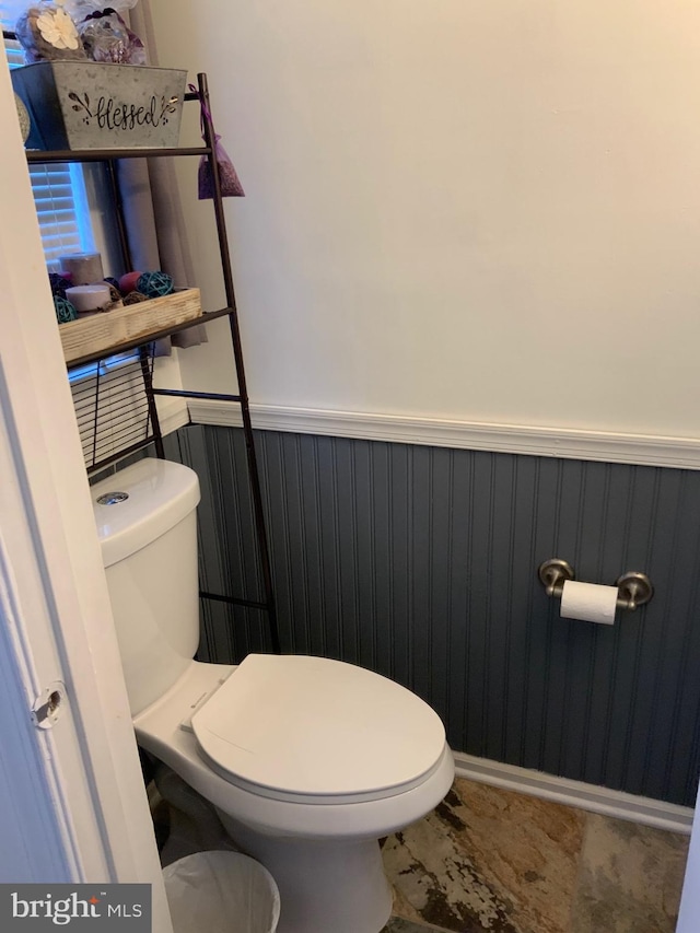 half bath with a wainscoted wall and toilet