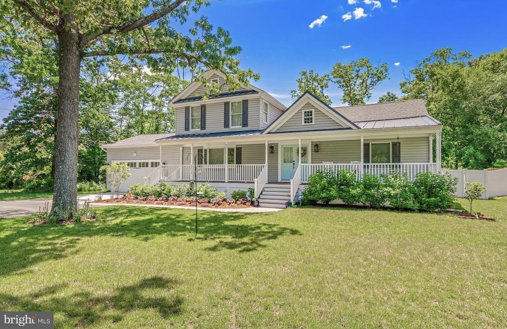 view of front of home featuring driveway, a front lawn, fence, covered porch, and a garage