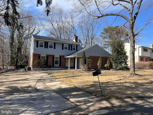 colonial inspired home featuring brick siding, driveway, and a chimney