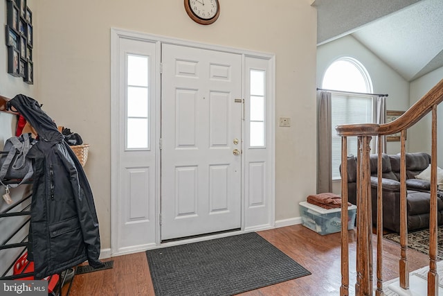 foyer entrance featuring lofted ceiling, stairs, baseboards, and wood finished floors