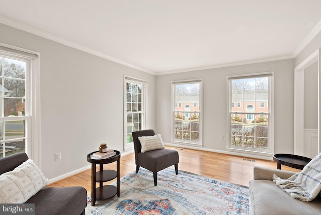 sitting room with ornamental molding, visible vents, light wood-style flooring, and baseboards