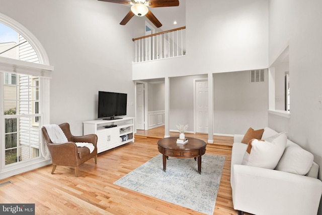 living room with wood finished floors, visible vents, and a ceiling fan