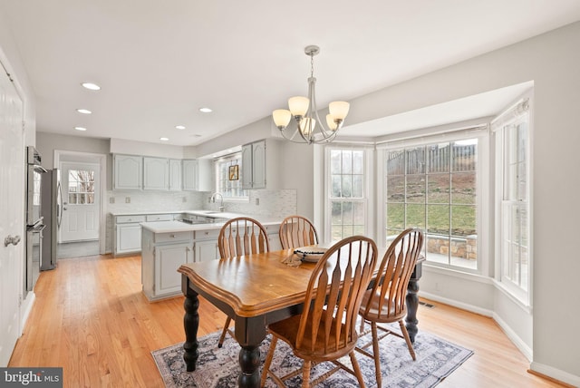 dining room featuring light wood-style floors, recessed lighting, a notable chandelier, and baseboards