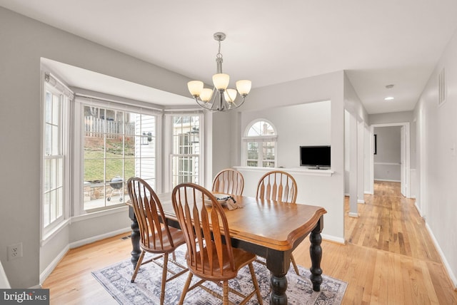 dining room with light wood finished floors, baseboards, and an inviting chandelier