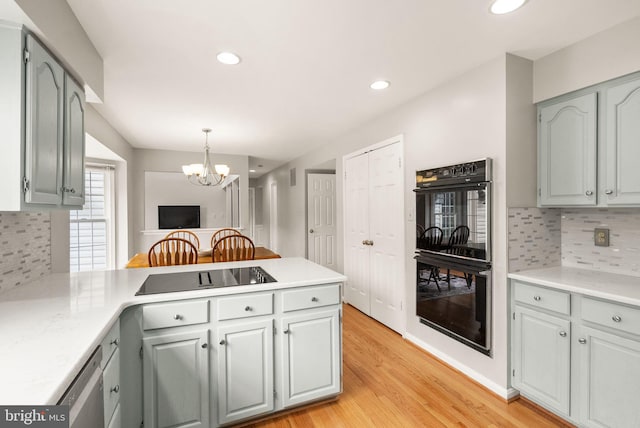 kitchen featuring black appliances, light wood finished floors, a peninsula, and light countertops