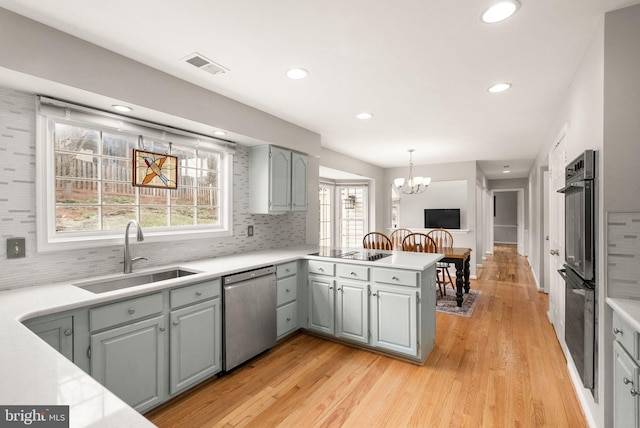 kitchen with light countertops, visible vents, a sink, and black appliances