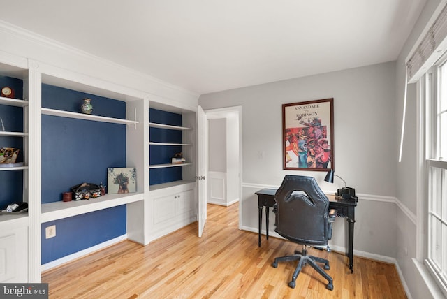 home office featuring built in shelves, baseboards, and wood finished floors