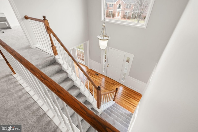 staircase with wood finished floors and a towering ceiling