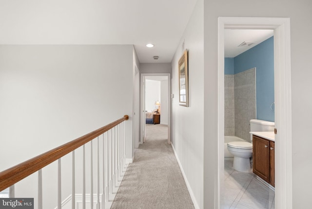 hall with an upstairs landing, recessed lighting, light carpet, and baseboards