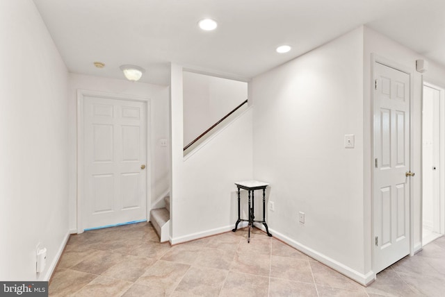 below grade area with recessed lighting, light tile patterned flooring, stairway, and baseboards