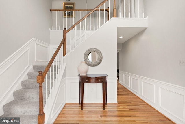 staircase with wood finished floors and a decorative wall