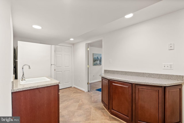 kitchen with freestanding refrigerator, light countertops, a sink, and recessed lighting