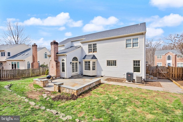 rear view of property featuring a yard, a fenced backyard, central AC, and a patio