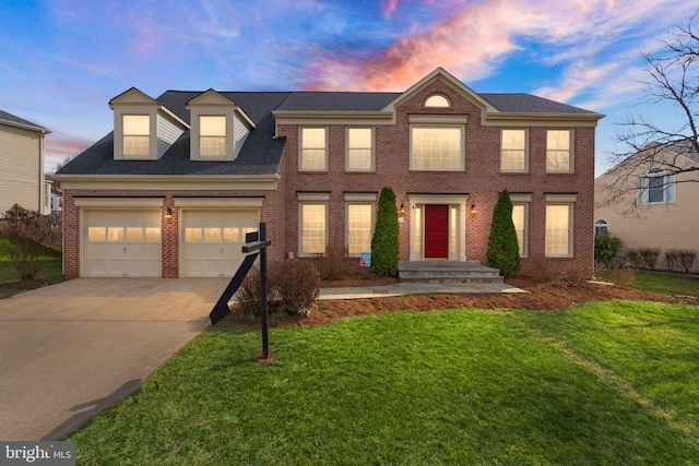 colonial home featuring a garage, concrete driveway, and brick siding