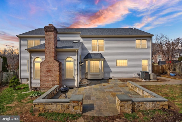 rear view of property featuring a patio area, a shingled roof, a chimney, and fence