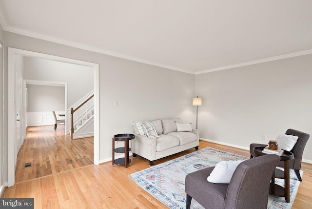 living room with visible vents, stairway, ornamental molding, light wood-type flooring, and baseboards