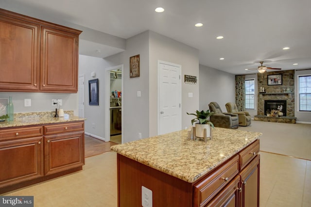 kitchen featuring a stone fireplace, recessed lighting, a ceiling fan, and light stone countertops